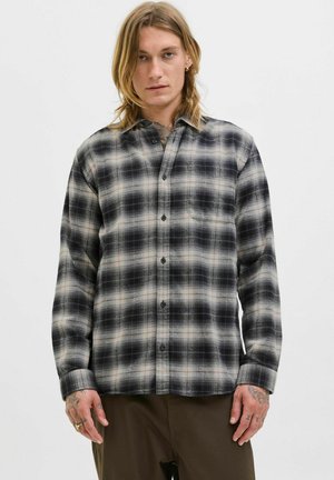 Camisa de franela con un patrón a cuadros en negro y gris, con botones en la parte delantera y un bolsillo en el pecho. Tejido suave con un corte holgado.