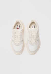 Baskets de sport blanches avec un dessus texturé, des accents beiges doux et des lacets ronds. Dotées d'une semelle rembourrée et d'un logo rayé subtil.