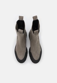 Ein Paar graue Wildleder Chelsea-Stiefel mit schwarzen Gummisohlen und Zuglaschen, von oben auf einem weißen Hintergrund betrachtet.