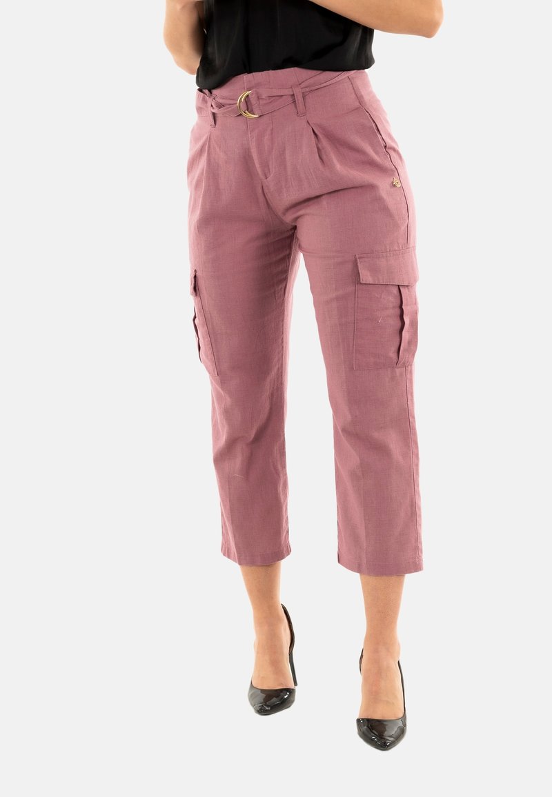 Pantalones cargo cortos rosas con cintura ceñida, dos bolsillos laterales y una textura suave, combinados con tacones altos negros.