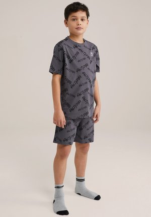 Ținută gri compusă dintr-un tricou și pantaloni scurți cu un model de text „SALTYDOG” în negru. Mânici scurte și șosete cu accente gri, negre și dungi.