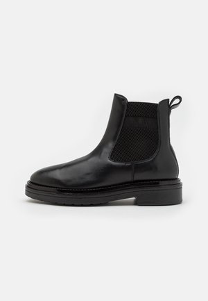 Black leather ankle boot featuring elastic side inserts, a rounded toe, and a chunky rubber sole for durability. Loop tab on the heel.