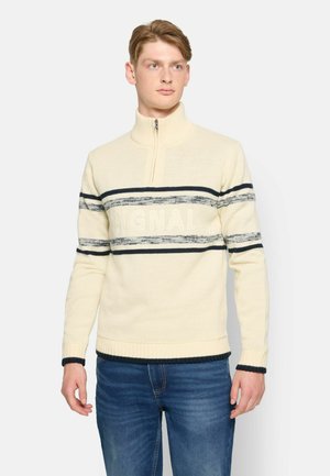 Cremefarvet sweater med høj krave, lynlås lukning, marineblå og grå vandrette striber, med "SIGNAL" tekst. Blød, struktureret strik.