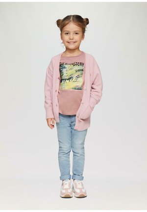 Jasnoróżowy sweter z teksturą i guzikami, graficzna różowa koszulka, jasnoniebieskie dżinsy oraz różowe trampki z białymi akcentami. Dziewczyna z dwoma kokami.