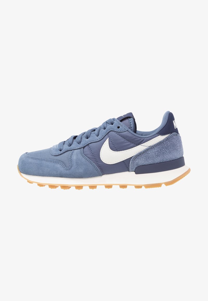 Blue suede sneaker with a white swoosh logo, featuring a textured upper, contrasting navy accents, and a gum rubber outsole.