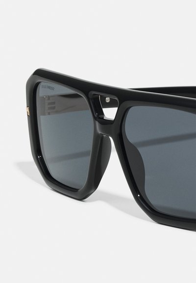 Black rectangular sunglasses with dark lenses, thick plastic frames, and a subtle gold accent near the hinge. Textured surfaces on the frame.