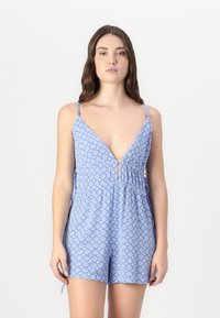 Mono corto azul con un estampado, escote en V profundo, tirantes delgados ajustables y cintura ceñida. Presenta diseños geométricos y pequeños acentos decorativos.