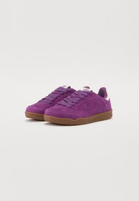 Lilla semskede sneakers med lavt design, som har en gummibrun sål, flade snørebånd og diskret branding på tungen.