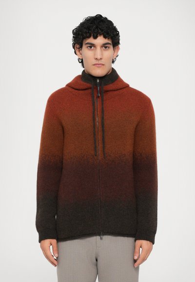 Hooded zip-up sweater with a gradient pattern transitioning from orange to dark brown. Made of a soft, textured material with drawstring accents.