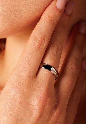 Zilveren ring met een gepolijste afwerking, met een glad, afgerond ontwerp. Draag op een vinger met zichtbare gedetailleerde huidtextuur.