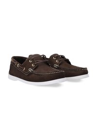 Braune Wildlederbootsschuhe mit weißen Gummisohlen, die über kontrastierendes weißes Nähen und Metallösen für die Schnürsenkel verfügen.