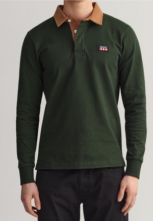 Dark green long-sleeve polo shirt with a brown corduroy collar, featuring a small logo on the left chest. Soft fabric, classic fit.