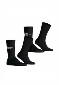 Schwarze Socken aus glattem Stoff mit geripptem Muster. Jede Socke zeigt ein weißes Logodetail an der Seite. Drei Paar abgebildet.