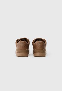 Brązowe skórzane sneakersy o gładkiej powierzchni, zaokrąglonym kształcie i gumowych podeszwach. Zawierają detale logo na pięcie.