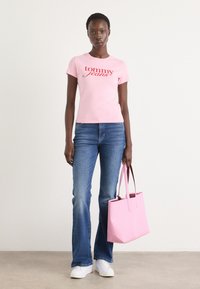 Lys rosa tettskjorte med "tommy jeans" logo, kombinert med vide blå denimjeans og en strukturert rosa totebag. Sneakers er hvite.