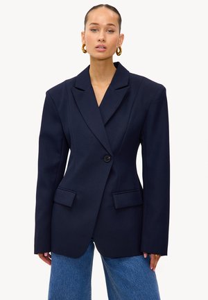 Marineblauer Oversize-Blazer mit strukturierten Schultern, spitzen Revers und zwei Vorderfachentaschen. Hergestellt aus glattem Stoff mit einem einzelnen Knopfverschluss.