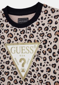 Felpa con stampa leopardata e colletto a coste neri, con un logo triangolare bianco con dettagli dorati e il nome del marchio in nero.