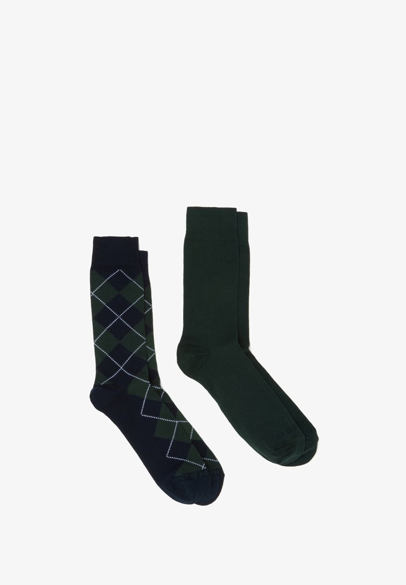 Dos pares de calcetines: uno azul marino con un patrón de diamantes verdes y el otro de un sólido verde oscuro. Ambos cuentan con una textura suave y un diseño tradicional.
