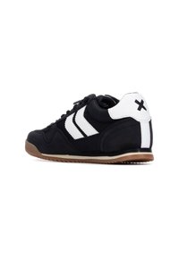 Zapatilla deportiva negra con parte superior de ante y sintético, que presenta un diseño de tres franjas blancas, suela de goma y un detalle en el talón con un símbolo '+' en negro.