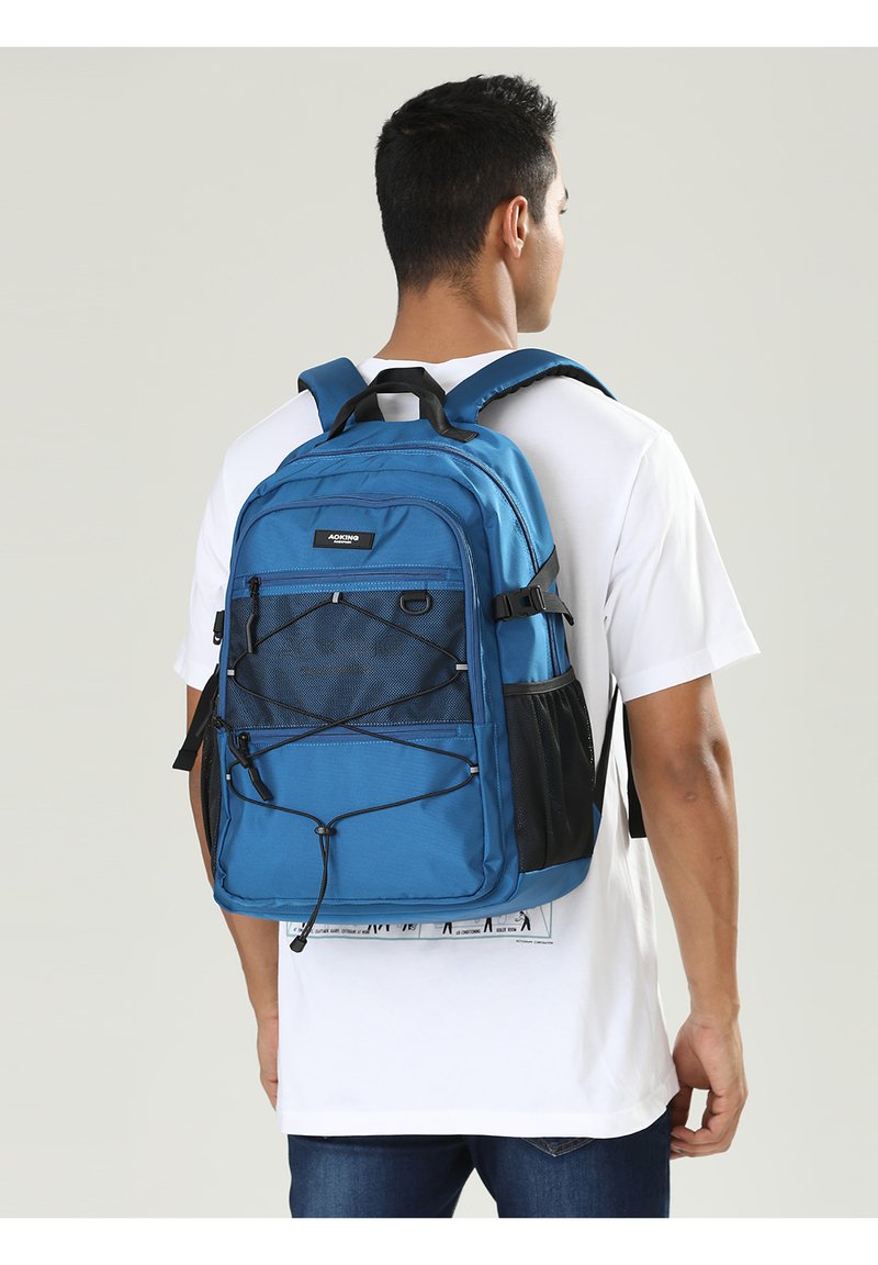Zaino blu realizzato in tessuto resistente, con un grande scomparto, pannello in rete, spallacci regolabili e una corda elastica frontale per ulteriore spazio di stivaggio.