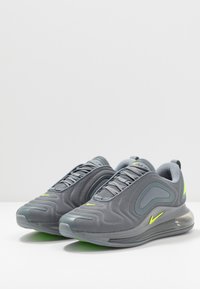 Szare buty sportowe z siateczkową cholewką, gumową podeszwą i poduszką powietrzną. Posiadają neonowo-żółte akcenty po bokach i w sznurowadłach.