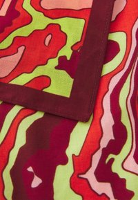 Cotton fabric with a wavy, abstract pattern in red, pink, green, and orange, featuring a maroon border and smooth texture.