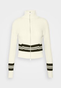 Pull blanc zippé avec col haut, rayures horizontales noires et blanches autour de la taille et des poignets, manches longues, texture côtelée.
