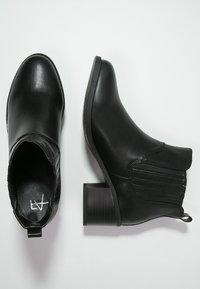 Czarne botki do kostki wykonane z gładkiej skóry, z niskim obcasem w kształcie bloku, elastycznymi bocznymi panelami oraz pętelką ułatwiającą zakładanie.