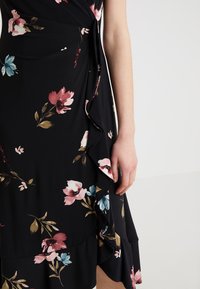 Abito nero a fiori con orlo arricciato, caratterizzato da motivi floreali rosa, blu e verdi. Realizzato in tessuto leggero, vestibilità aderente.