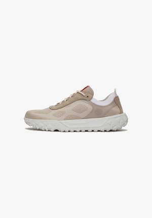 Chaussure de sport beige clair avec tige en tissu tricoté, semelle épaisse blanche à crampons, fermeture lacée à l'avant et languette au talon.