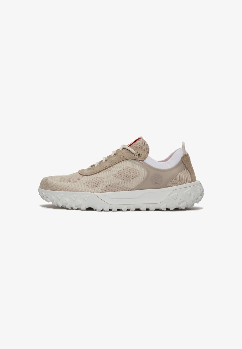 Chaussure de sport beige clair avec tige en tissu tricoté, semelle épaisse blanche à crampons, fermeture lacée à l'avant et languette au talon.