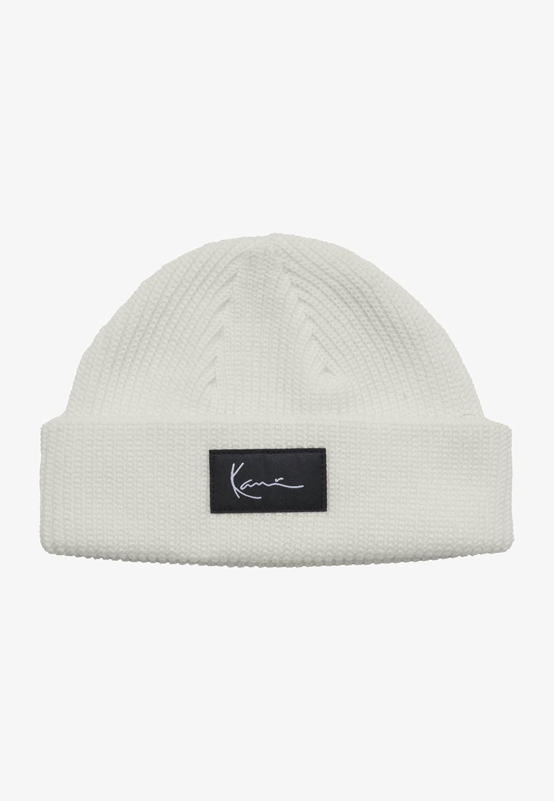 White knitted beanie with folded cuff featuring a black rectangular patch and white cursive "Kani" logo on the front.