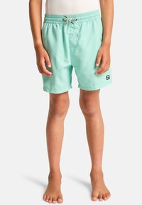 Shorts de bain turquoise en tissu léger. Dotés d'une taille élastique avec un cordon de serrage et d'un patch logo sur le côté.