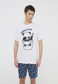 T-shirt bianco in cotone con una grafica di un panda in una tazza e il testo "Feeling Fresh!" abbinato a pantaloni corti blu decorati con panda.