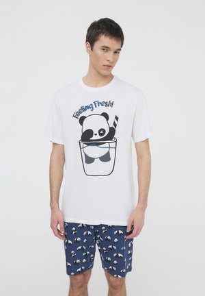 T-shirt bianco in cotone con una grafica di un panda in una tazza e il testo "Feeling Fresh!" abbinato a pantaloni corti blu decorati con panda.