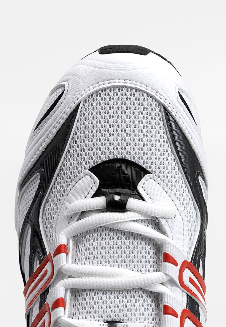 Białe siatkowe buty sportowe z czarnymi i czerwonymi akcentami, z chropowatym czubkiem, plecionymi sznurówkami i smukłym, aerodynamicznym kształtem.