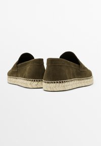 Brown suede slip-on shoes with a woven jute sole and contrasting stitching. Soft texture and rounded back design for comfort.