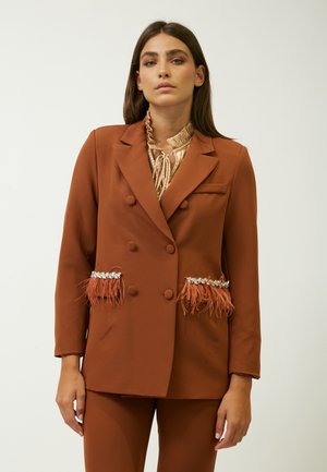 Blazer marrón de doble botonadura con detalles de plumas y bolsillos decorados. Tejido suave, corte entallado y mangas largas.