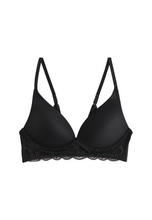 Schwarzer BH mit glatten Cups und Spitzenbesatz, getragen auf nackter Haut, zeigt Dekolleté und einen sichtbaren Muttermal nahe der Schulter.