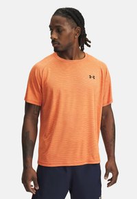 Camiseta deportiva de manga corta para hombres en un vibrante color naranja con un sutil patrón de rayas, escote redondo y logo negro en el pecho.