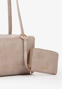 Borsa a tracolla in finta pelle beige con texture a coccodrillo, dettagli in oro e una pochette coordinata con chiusura a zip.