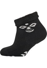 Svart ankelstrumpa med en texturerad överkant. Har en vit tecknad ansiktsdesign och vita accenspilar nära tån. Klassisk ribbad struktur.