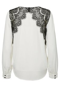 Blusa bianca a maniche lunghe con dettagli in pizzo nero sul retro, scollatura rotonda e bottoni alle maniche. Texture liscia.