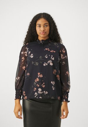 Blouse marine à imprimé floral en rose et crème. Présente un col haut avec des détails en volants et des manches transparentes avec des poignets froncés.
