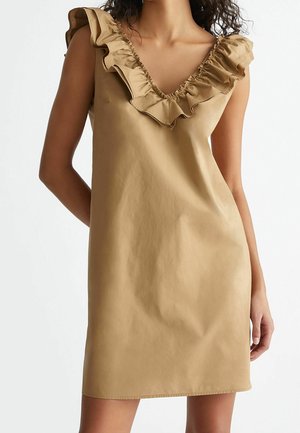 Vestido sin mangas color arena con escote en V profundo y volantes en los bordes. Material suave y ligero con un brillo sutil.