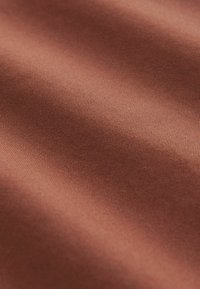 Tissu satin brun avec une texture lisse et brillante. La surface présente de subtils reflets de lumière et un motif de tissage fin et constant.