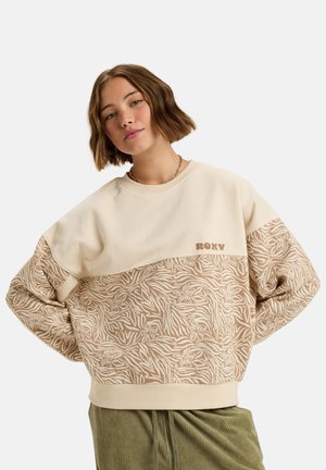 Cream and tan Roxy sweatshirt with floral pattern on lower half, ribbed cuffs, and crew neckline. Soft fabric with relaxed fit.