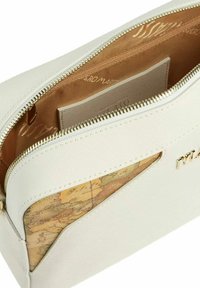 Borsa bianca con texture e dettaglio cartografico, zip dorata e logo. Interno foderato in beige con tasca a soffietto.