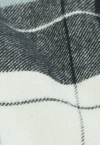 Geruit stof met grijze en witte kleuren. Gladde textuur met een geweven patroon, met contrasterende donkere en lichte lijnen.