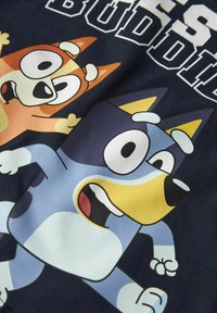 Granatowa tkanina z graficznym nadrukiem dwóch rysunkowych psów w intensywnym pomarańczowym i niebieskim kolorze, z wyraźnymi konturami i dużymi, ekspresyjnymi oczami.